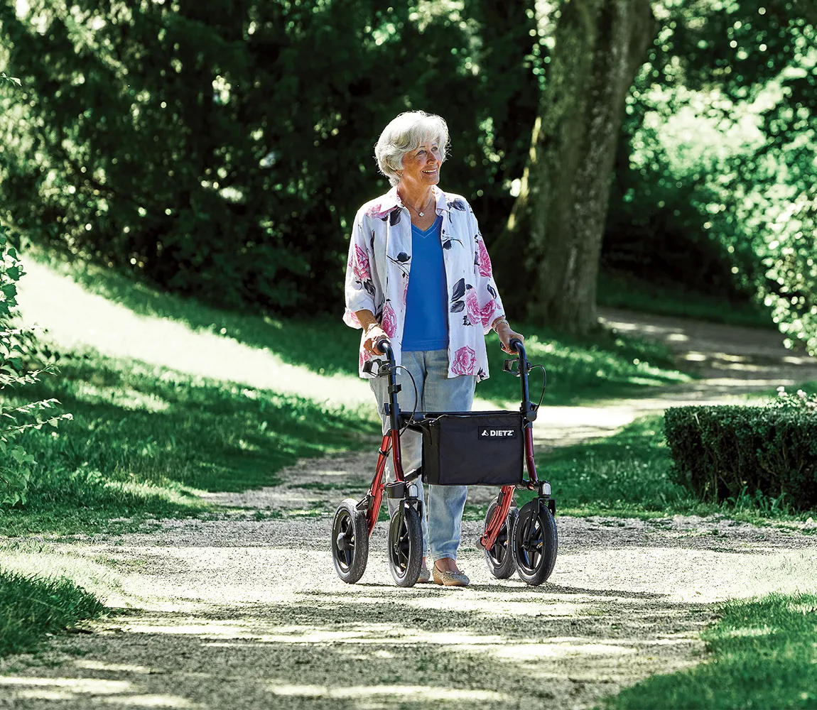 Rollator Taima XC von Dietz, mit Luftbereifung, Frau geht im Park am Rollator spazieren
