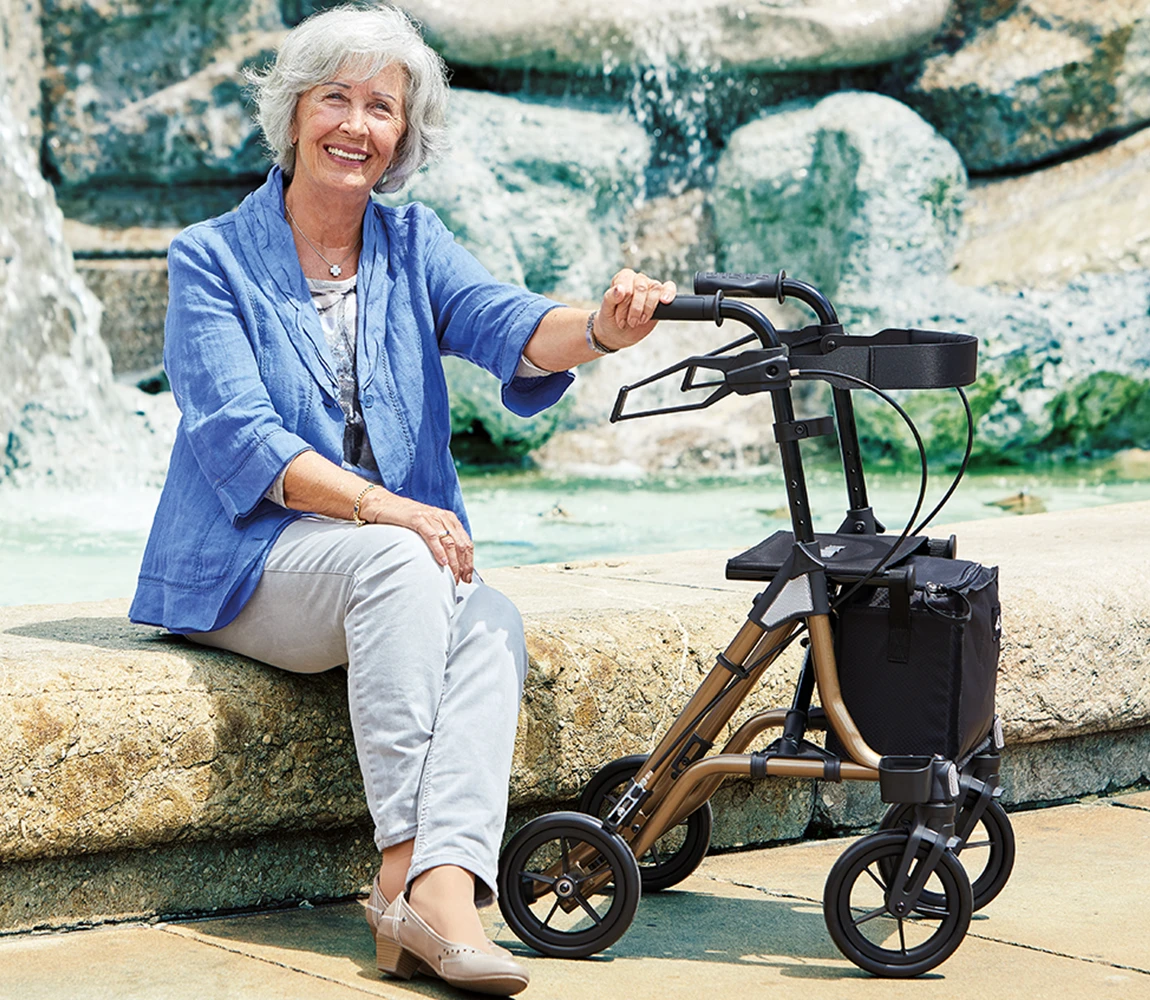 Rollator Taima S GT in Benutzung eine Frau sitzt am Brunnen und hält den Rollator Taima S GT fest